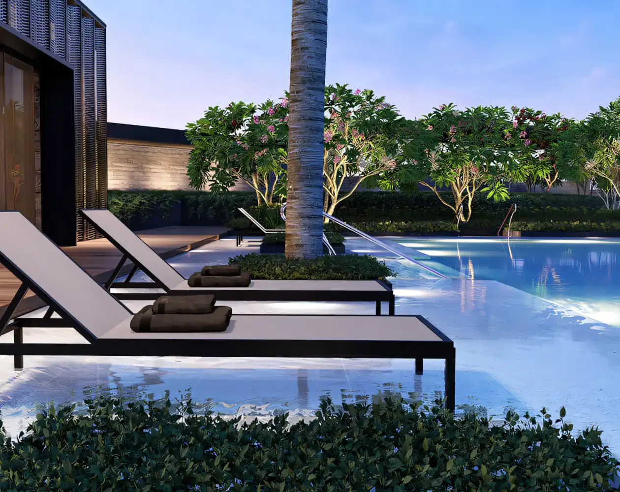 Tranquil pool area with sun loungers set beside a glistening pool. Surrounded by greenery and trees, creating a relaxing oasis atmosphere.
