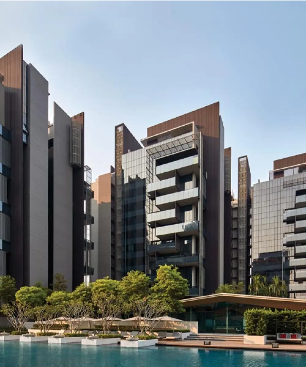 Contemporary residential blocks at Leedon Residences with a sleek, angular design overlooking a large outdoor pool surrounded by trees and greenery.